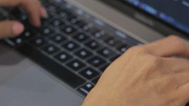 A person's hands typing on a laptop
