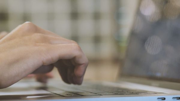 Hands typing on a laptop